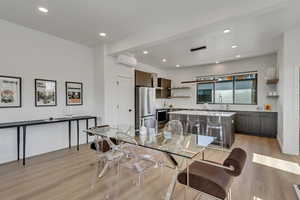 Dining area with recessed lighting, light wood finished floors, and a wall mounted air conditioner