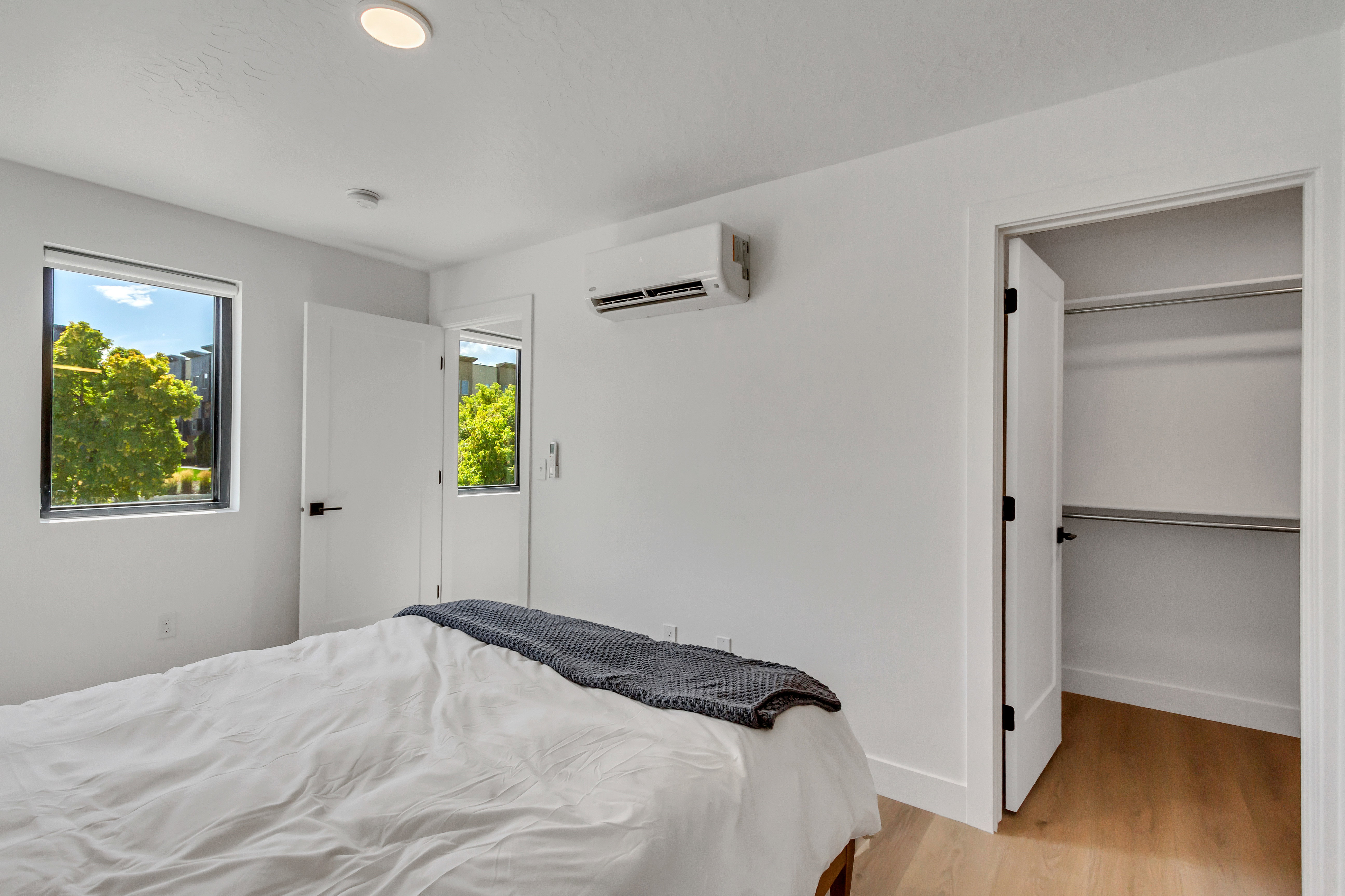 Bedroom featuring light wood-style flooring, a wall unit AC, and a spacious closet