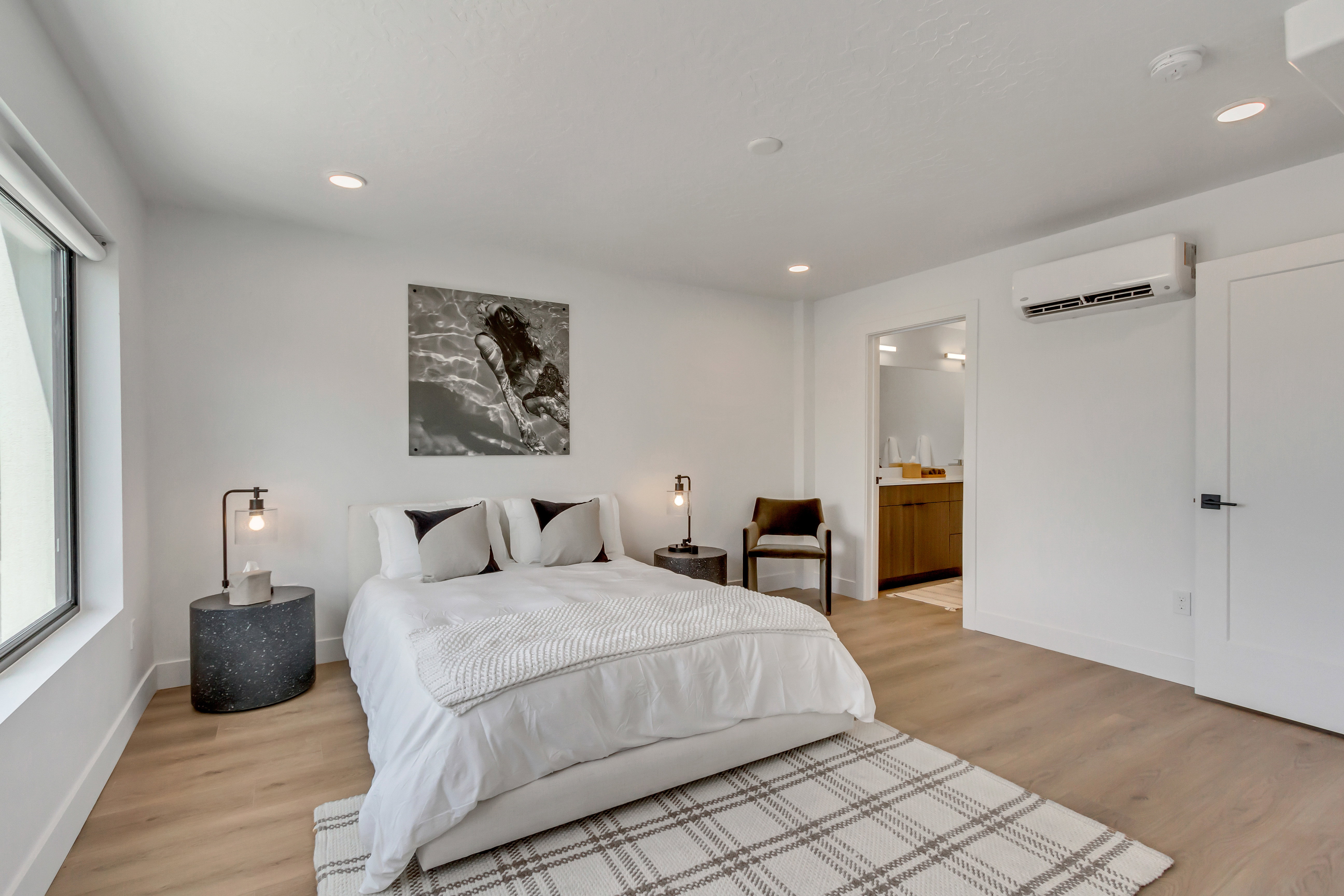 Bedroom featuring recessed lighting, light wood-style flooring, a wall mounted AC, and connected bathroom