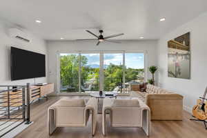 Living room with ceiling fan, light wood finished floors, recessed lighting, and a wall mounted AC