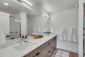 Bathroom featuring double vanity, a shower stall, and dark wood-type flooring