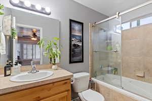 Ensuite bathroom featuring vanity, tiled shower / bath, and ceiling fan