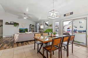 Dining area featuring vaulted ceiling, light tile patterned floors, and a ceiling fan
