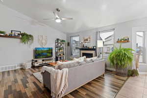 Living room featuring a tiled fireplace, wood-type flooring, and a ceiling fan