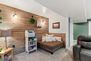 Living area with wood walls, carpet floors, and an accent wall