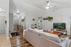 Living area with lofted ceiling, a ceiling fan, and light wood-style floors