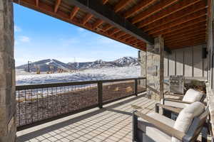 Snow covered patio featuring a mountain view, a grill, and a patio
