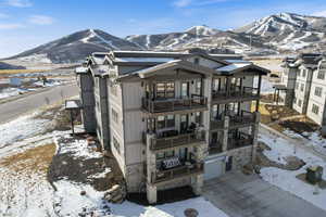 View of front of property featuring a mountain view, stone siding, and a balcony