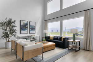 Living area featuring a towering ceiling, light wood-style flooring, and a mountain view