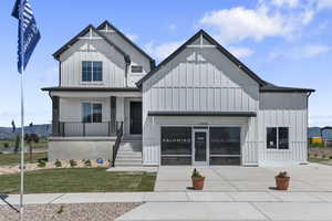 View of front of house featuring board and batten siding, a front yard, covered porch, and a mountain view