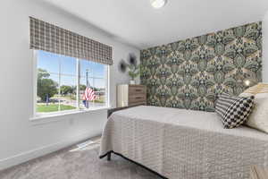 Carpeted bedroom with an accent wall and baseboards