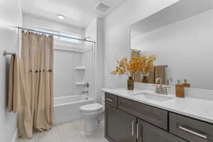 Full bath featuring a textured ceiling, shower / tub combo, vanity, and light tile patterned flooring