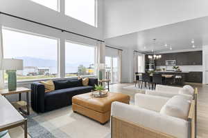 Living room featuring a chandelier, a mountain view, light wood-style floors, a towering ceiling, and recessed lighting