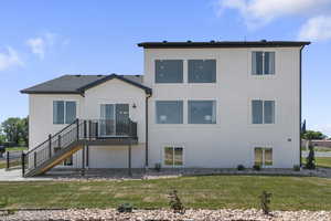 Back of house with a yard, a wooden deck, stairway, and stucco siding