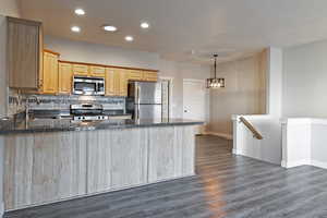 Kitchen with a peninsula, stainless steel appliances, recessed lighting, light brown cabinets, and tasteful backsplash