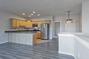 Kitchen with stainless steel appliances, hanging light fixtures, a peninsula, dark wood-type flooring, and recessed lighting