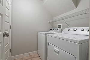 Laundry area with washer and clothes dryer and light tile patterned floors