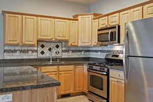 Kitchen featuring stainless steel appliances, tasteful backsplash, light tile patterned floors, tile counters, and light brown cabinets