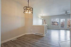 Unfurnished room featuring dark wood-type flooring, a chandelier, and a ceiling fan