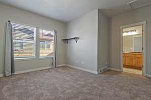 Unfurnished bedroom with light colored carpet and connected bathroom