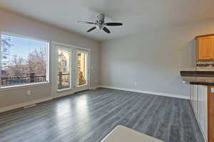 Unfurnished living room with dark wood-style flooring and ceiling fan