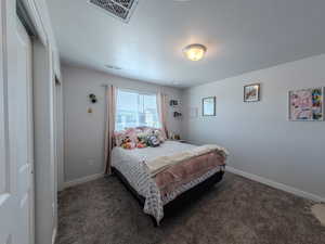 Carpeted bedroom featuring baseboards and a textured ceiling