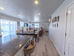 Kitchen with light wood-style flooring, dark stone counters, recessed lighting, open floor plan, and a breakfast bar