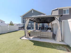 Back of house with a gate, a patio area, a fenced backyard, a gazebo, and an outdoor living space