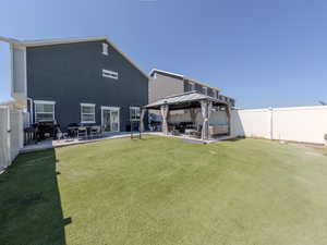 Back of house with a fenced backyard, a gazebo, a patio area, and an outdoor hangout area
