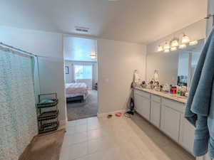 Ensuite bathroom featuring vanity, a textured ceiling, a shower with curtain, and light tile patterned floors