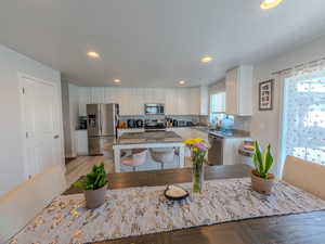 Kitchen featuring recessed lighting, white cabinets, dark stone countertops, stainless steel appliances, and a center island