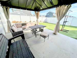 Fenced backyard featuring an outdoor living space, a gazebo, and a patio