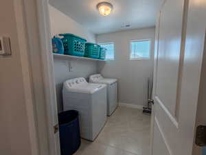 Laundry room featuring washing machine and clothes dryer and light tile patterned floors