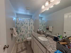 Full bath with vanity, curtained shower, and light tile patterned flooring