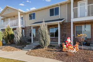 View of front of property with a balcony and brick siding