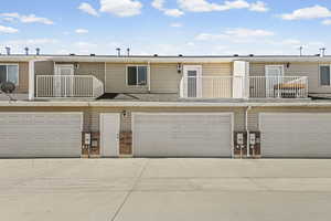 View of front of property with a balcony, concrete driveway, an attached garage, and brick siding