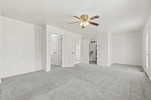 Unfurnished bedroom featuring light carpet, ceiling fan, and ensuite bath