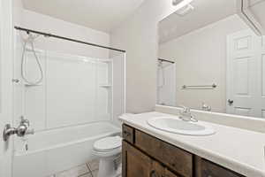 Bathroom with washtub / shower combination, vanity, and light tile patterned floors