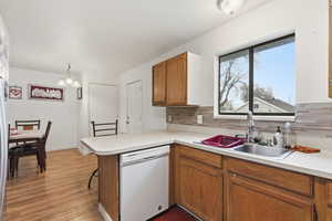 Kitchen with white appliances, brown cabinetry, light countertops, a peninsula, and tasteful backsplash