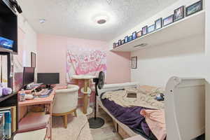 Bedroom featuring a desk, light wood finished floors, and a textured ceiling