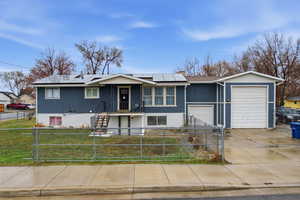 Single story home with concrete driveway, a fenced front yard, an attached garage, and stucco siding