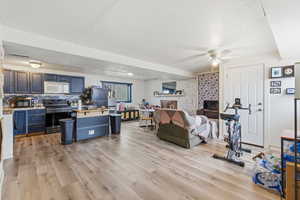 Living area with a textured ceiling, a ceiling fan, and light wood-style flooring