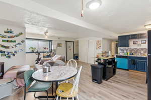 Dining room featuring light wood finished floors, a ceiling fan, and a textured ceiling