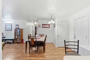 Dining area with light wood-style floors, a chandelier, and a textured ceiling