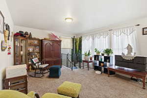 Living area featuring light carpet and an upstairs landing