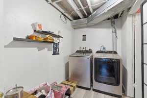 Laundry room with washing machine and clothes dryer and light wood-type flooring