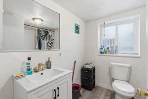 Full bathroom with vanity, a textured ceiling, light wood finished floors, a shower with shower curtain, and a textured wall