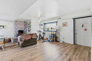 Interior space with a textured ceiling, light wood-style floors, an accent wall, and ceiling fan