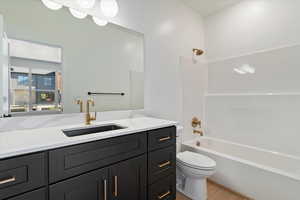 Bathroom featuring washtub / shower combination, vanity, and light wood finished floors