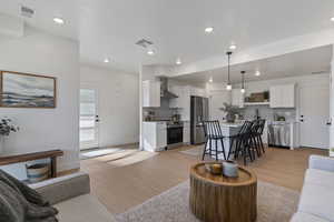 Living room with light wood-type flooring and recessed lighting